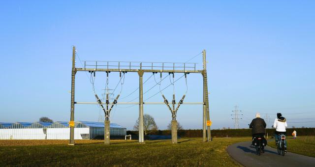 Hoogspanningskabels met 2 fietsers ernaast