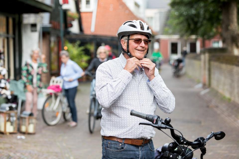 Man maakt helm vast aan hoofd en zit op fiets.