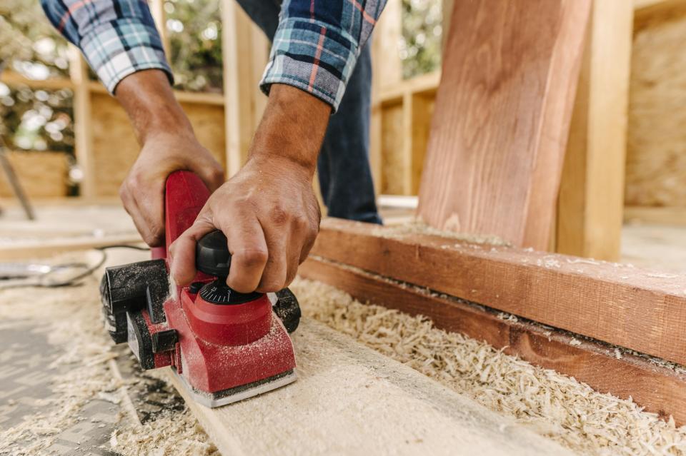 Man met een machine hout aan het schuren