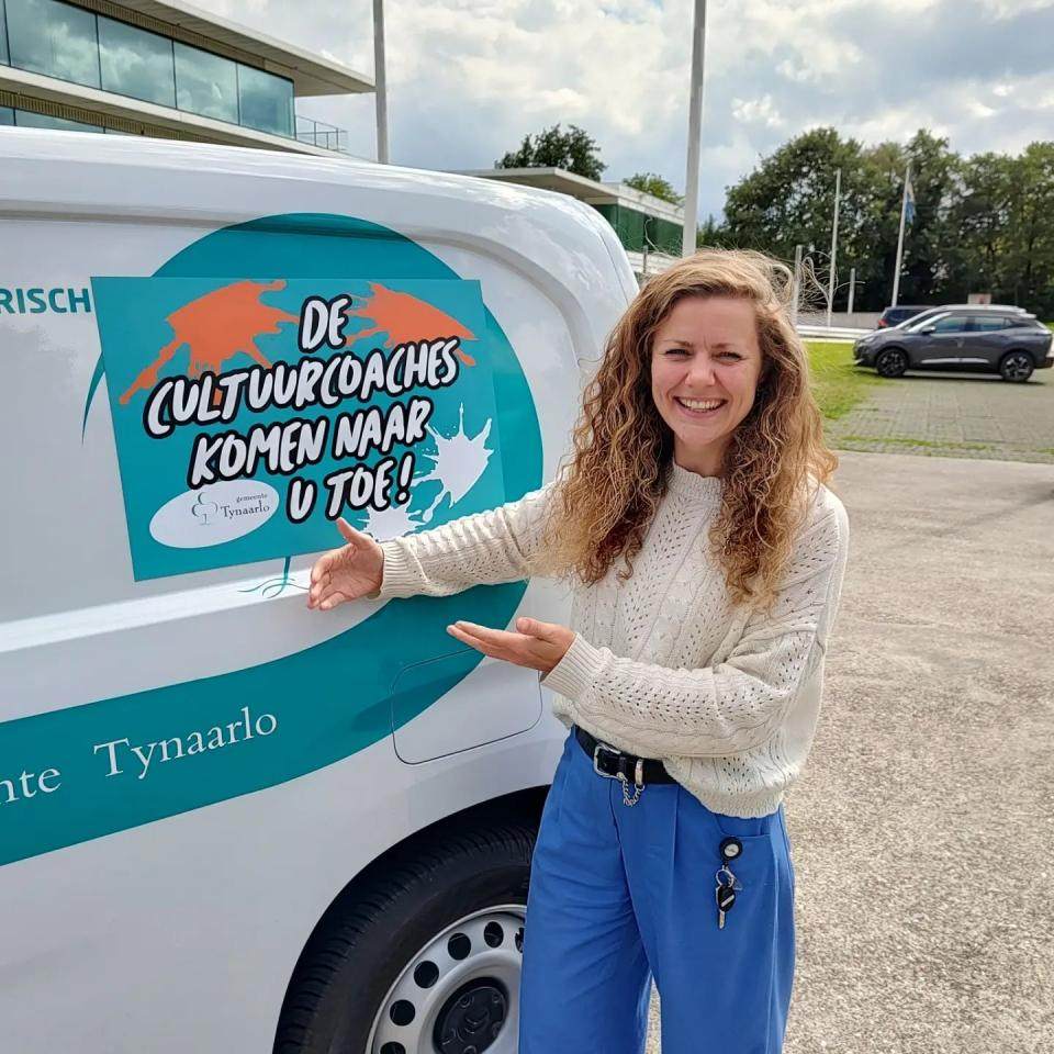 Cultuurcoach Lotte Jansen laat de magneetsticker op de auto van de gemeente zien.