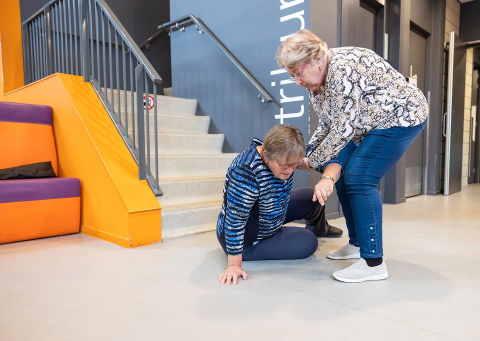 Gevallen vrouw wordt geholpen bij het opstaan