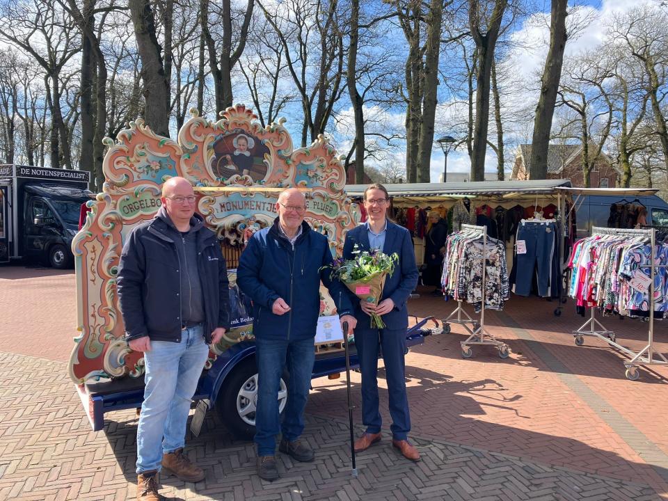 Marktkoopman Henk naast zijn zoon en wethouder Kuipers, samen voor een draaiorgel.