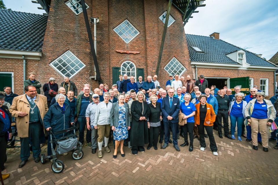 Prinses Beatrix staat tussen een groep vrijwilligers van molen De Wachter in Zuidlaren