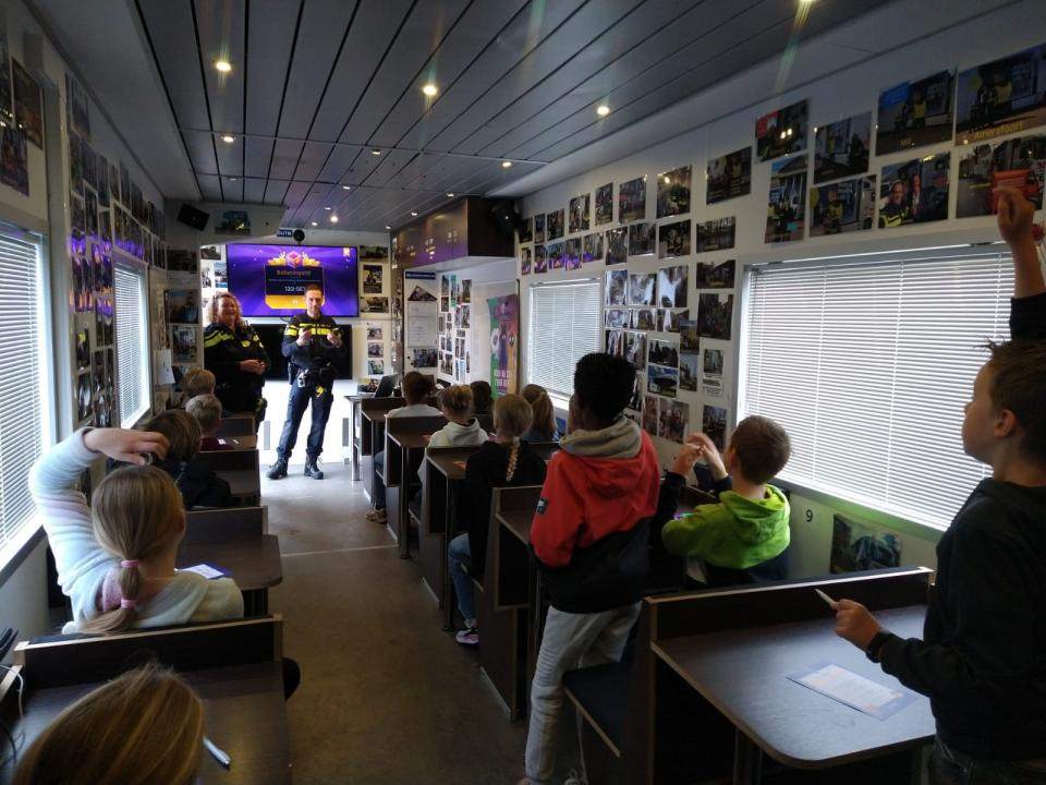 Schoolkinderen in een grote vrachtwagen waar ze uitleg krijgen over de gevaren van internet