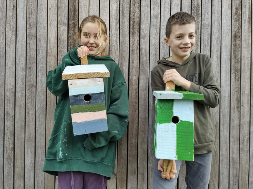 Twee kinderen houden nestkastjes vast die ze hebben beschilderd 