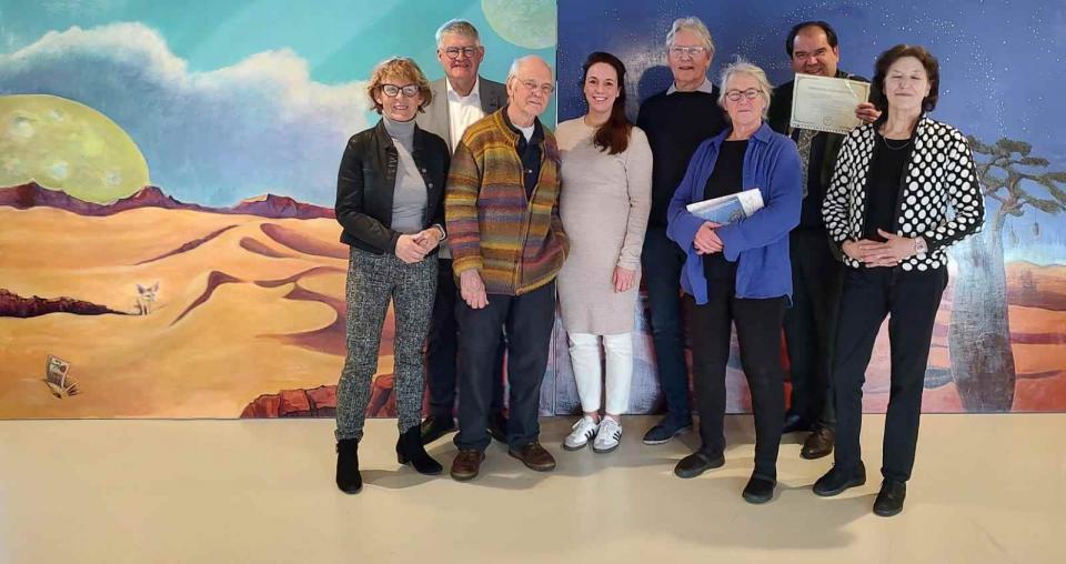Kunstenaars, rotaryleden, vertegenwoordiger van het Taalhuis en burgemeester Thijsen voor twee grote schilderijen met daarop een woestijnlandschap
