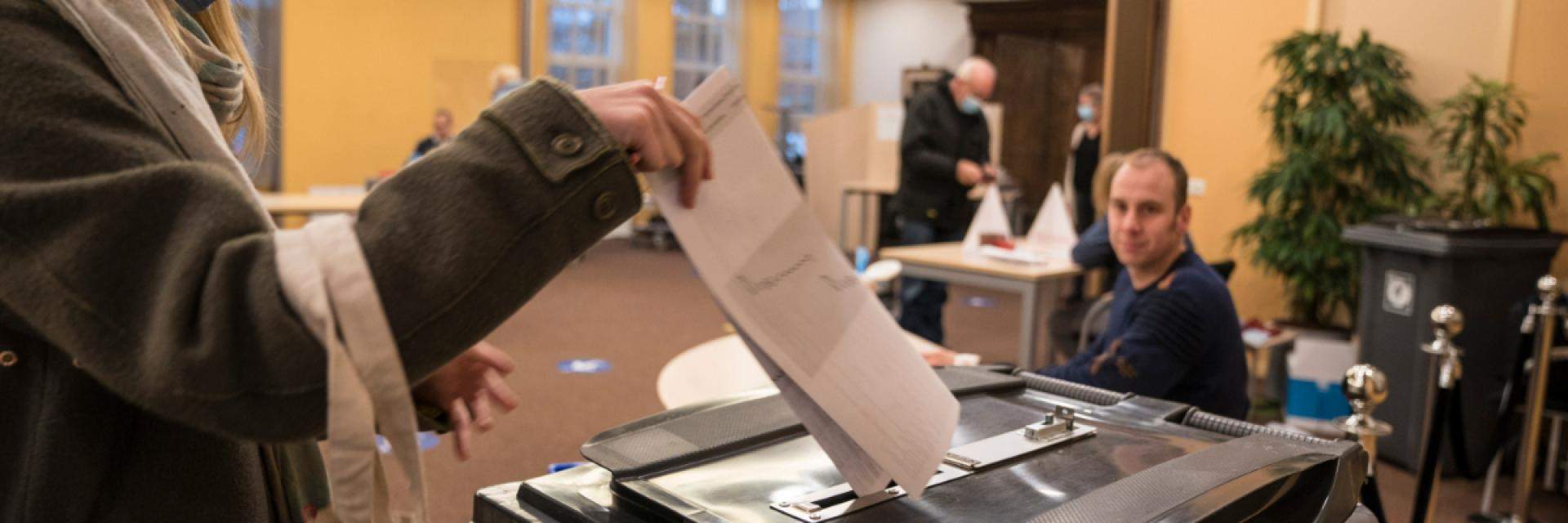 Decoratieve afbeelding van iemand die een stembiljet in de stembus steekt